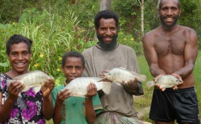 Papua New Guinean family holding fish